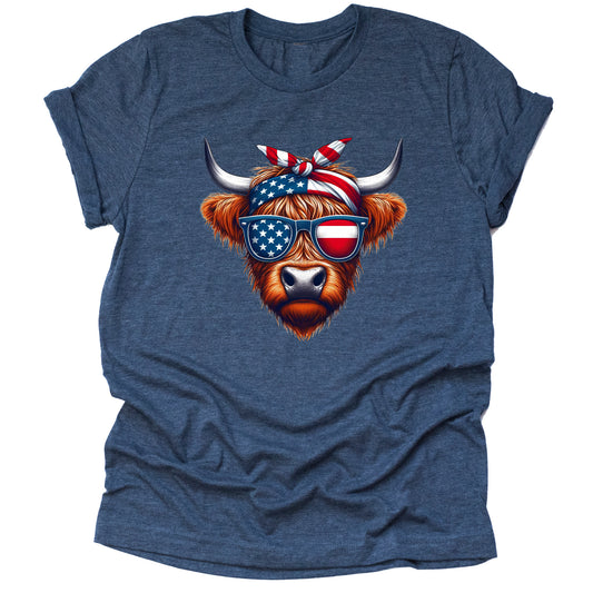 A navy short-sleeved unisex T-shirt featuring a graphic of a Highland cow with American flag patterned sunglasses and a bow.