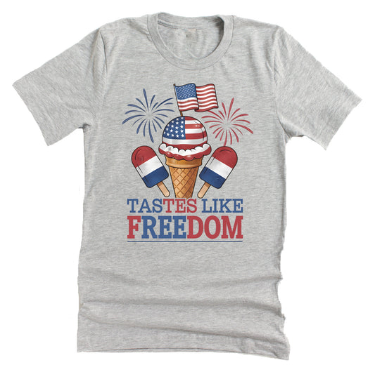 A casual short-sleeve unisex T-shirt with a graphic that includes an ice cream cone with the American flag and the text 'TASTES LIKE FREEDOM' on it, in a light blue color.
