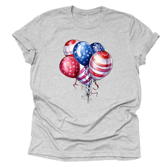 A casual short-sleeve unisex T-shirt in a light grey color, featuring a design of red, white, and blue balloons with stars and stripes, reminiscent of the American flag.