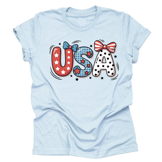 A light blue unisex short-sleeve T-shirt with a cute patriotic USA graphic design featuring bows, stars and stripes.